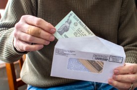 Sobre muestra a una persona sacando un cheque de estímulo, que es un alivio económico